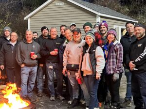 Catania employees smiling around a portable fire pit at the 2025 Turkey Fry